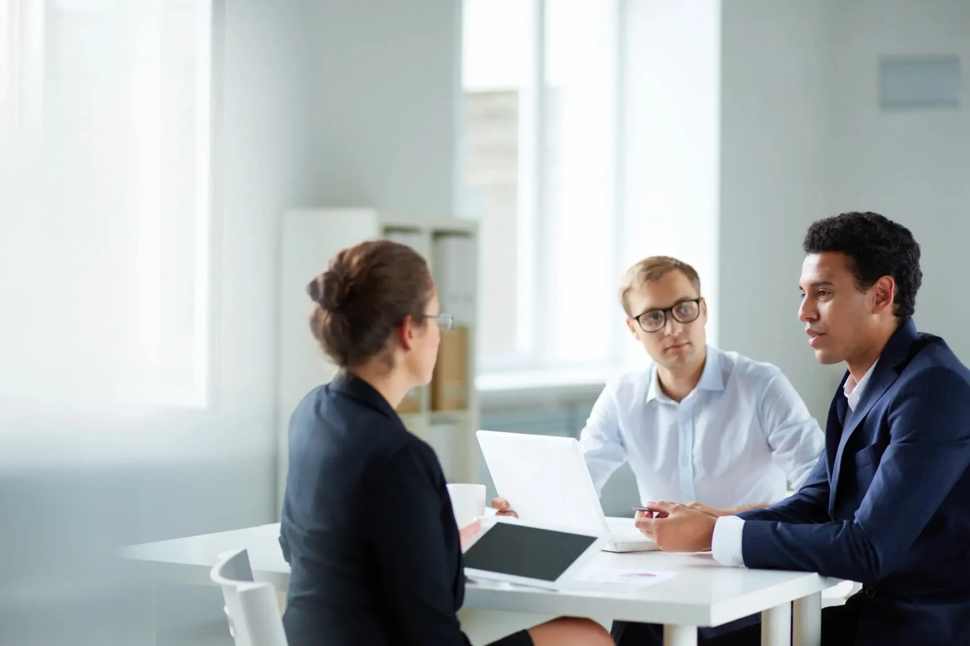 Three people sitting at a table with laptops