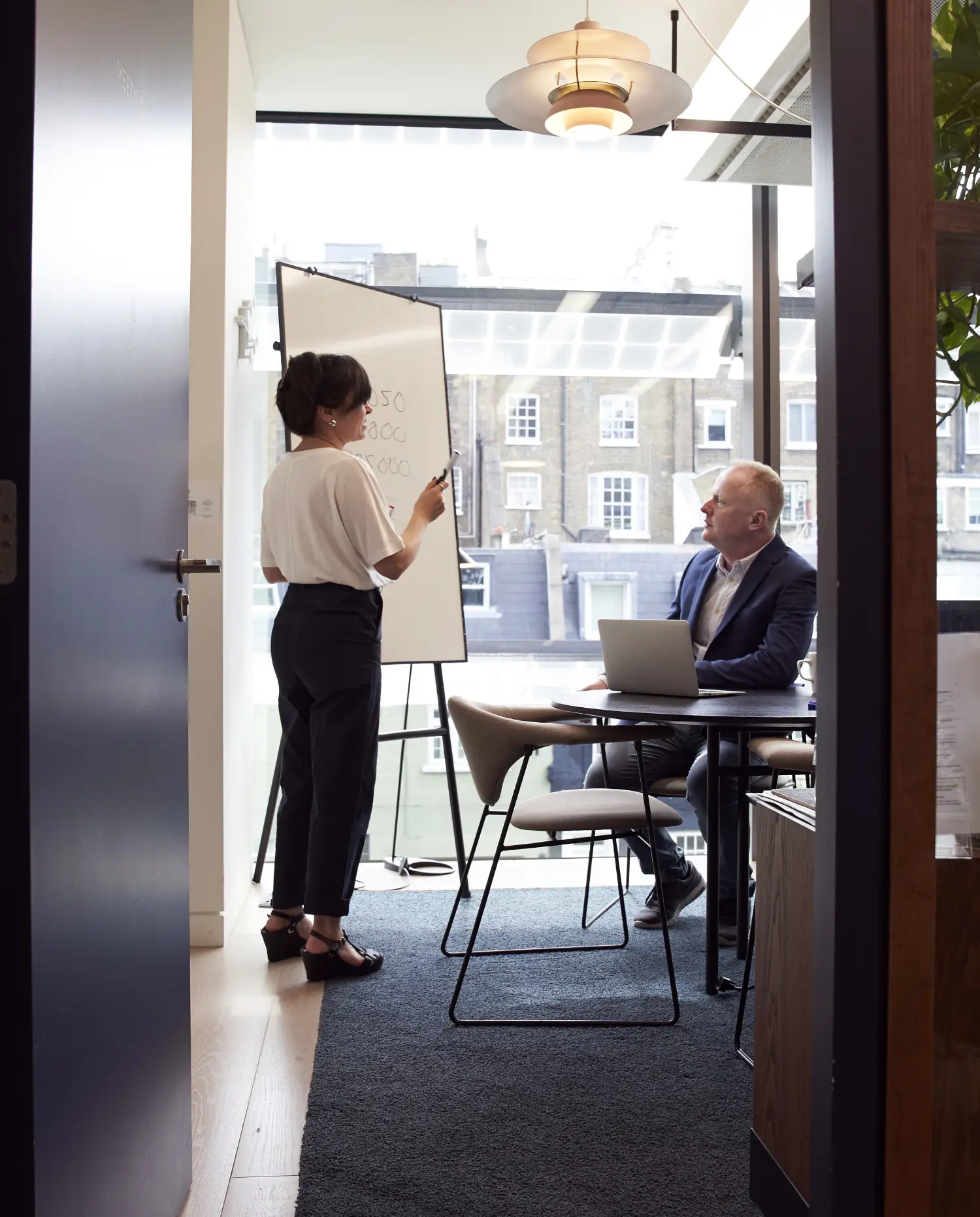 A woman standing next to a man in front of a flip chart.